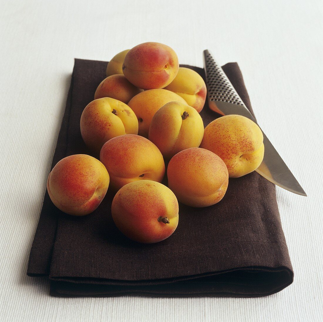 Apricots with knife on brown cloth