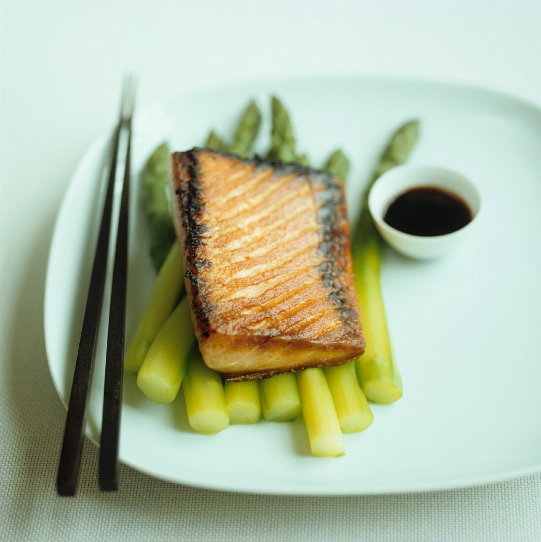 Teriyaki salmon on green asparagus with soy sauce