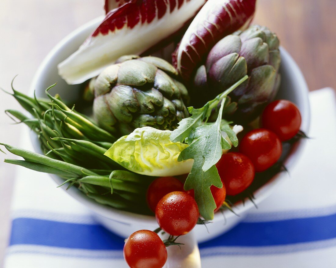 A bowlful of fresh vegetables (tomatoes, beans, artichokes)