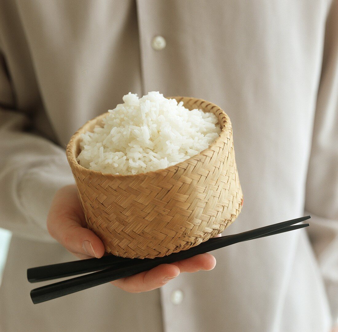 A man holding a bamboo basket filled with rice
