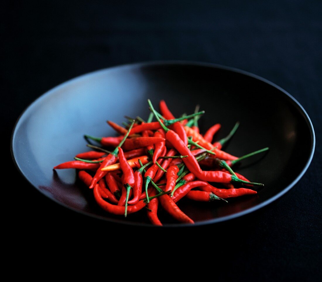 Red birds-eye chilli peppers in a black bowl