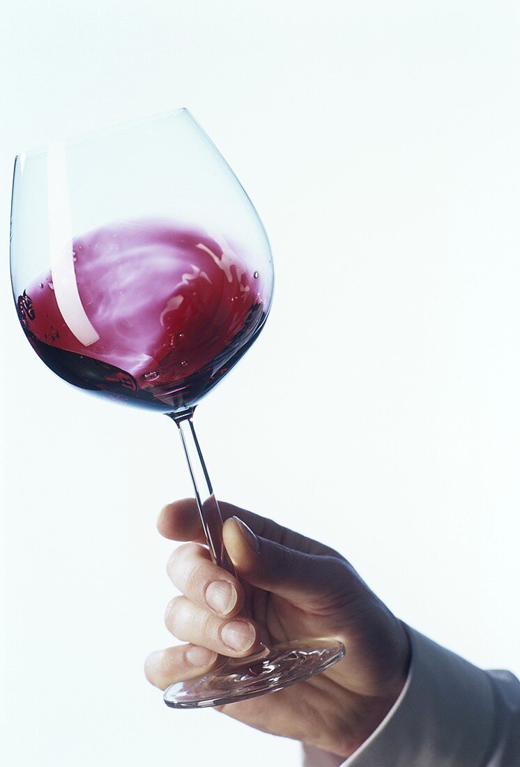 Wein lüften: Hand schwenkt ein Glas Rotwein