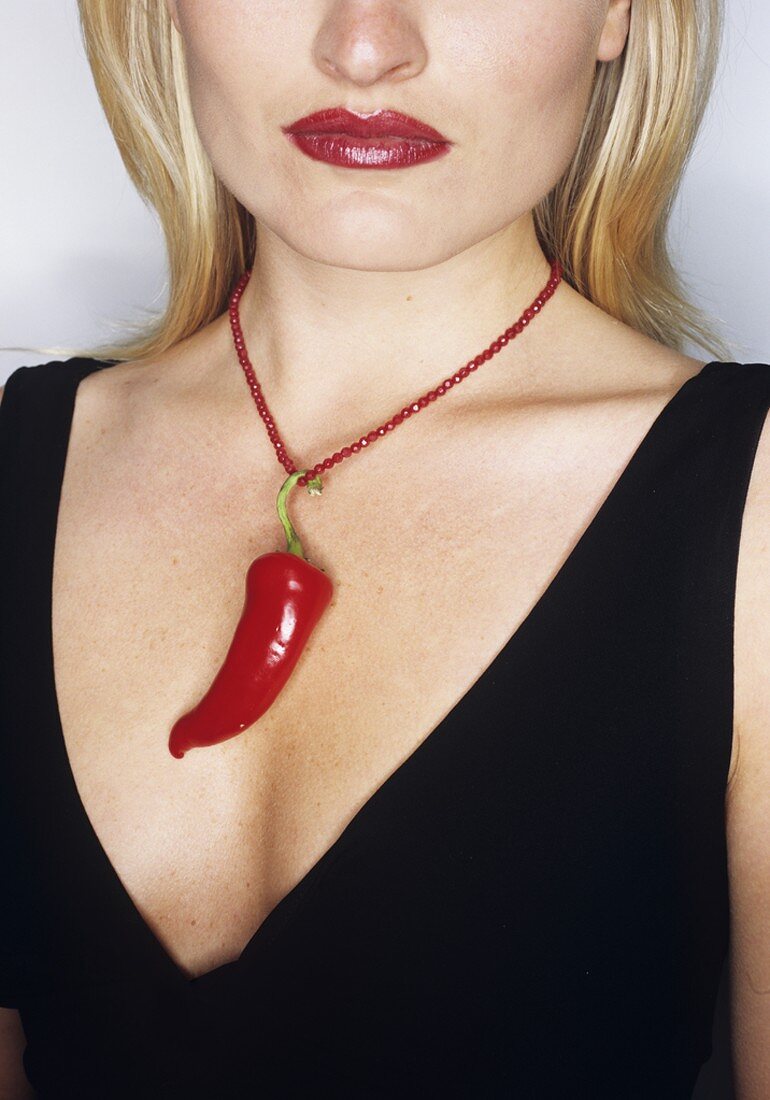 Frau trägt rote Chilischote als Kettenanhänger