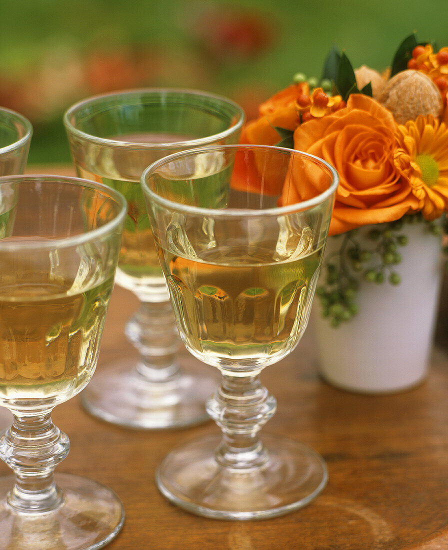 Weißwein in Gläsern und herbstlicher Blumenstrauss