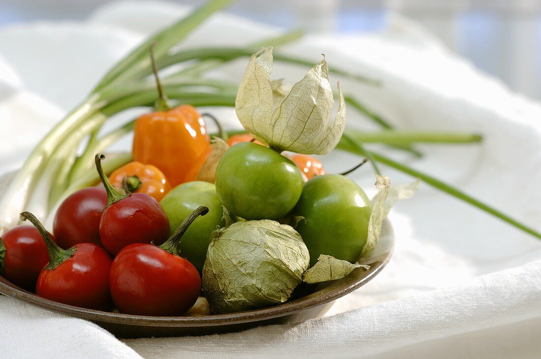 Tomatillos, chillies and spring onions on plate