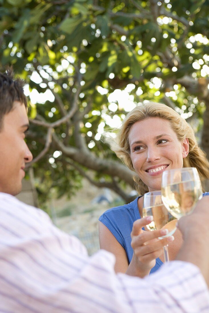 Man and woman raising glasses of white wine out of doors