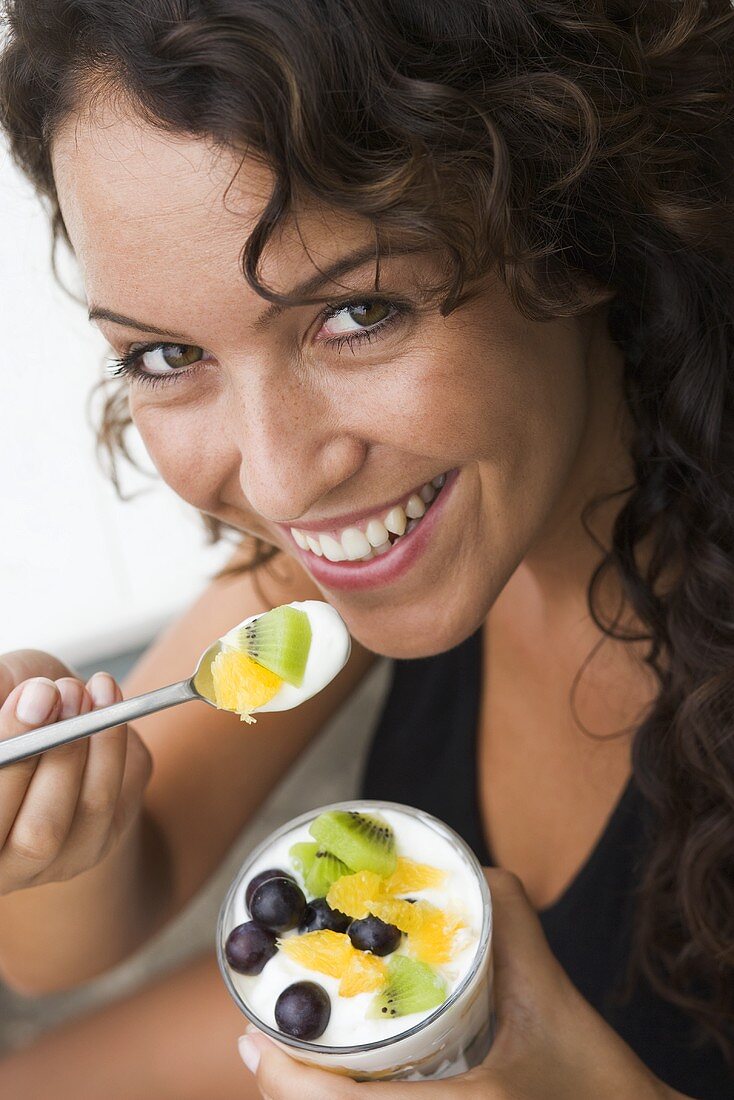 Frau isst Joghurt mit frischen Früchten