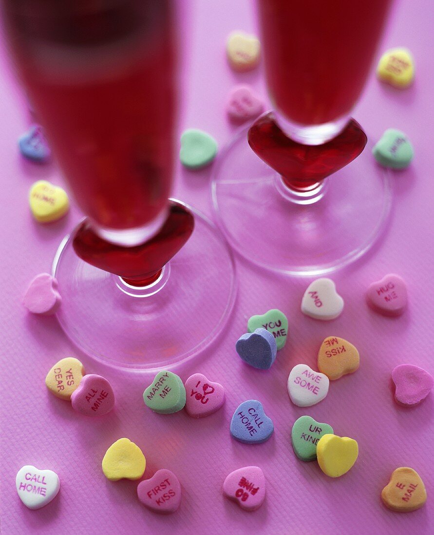 Herzförmige Zuckerbonbons und zwei Gläser mit rotem Cocktail