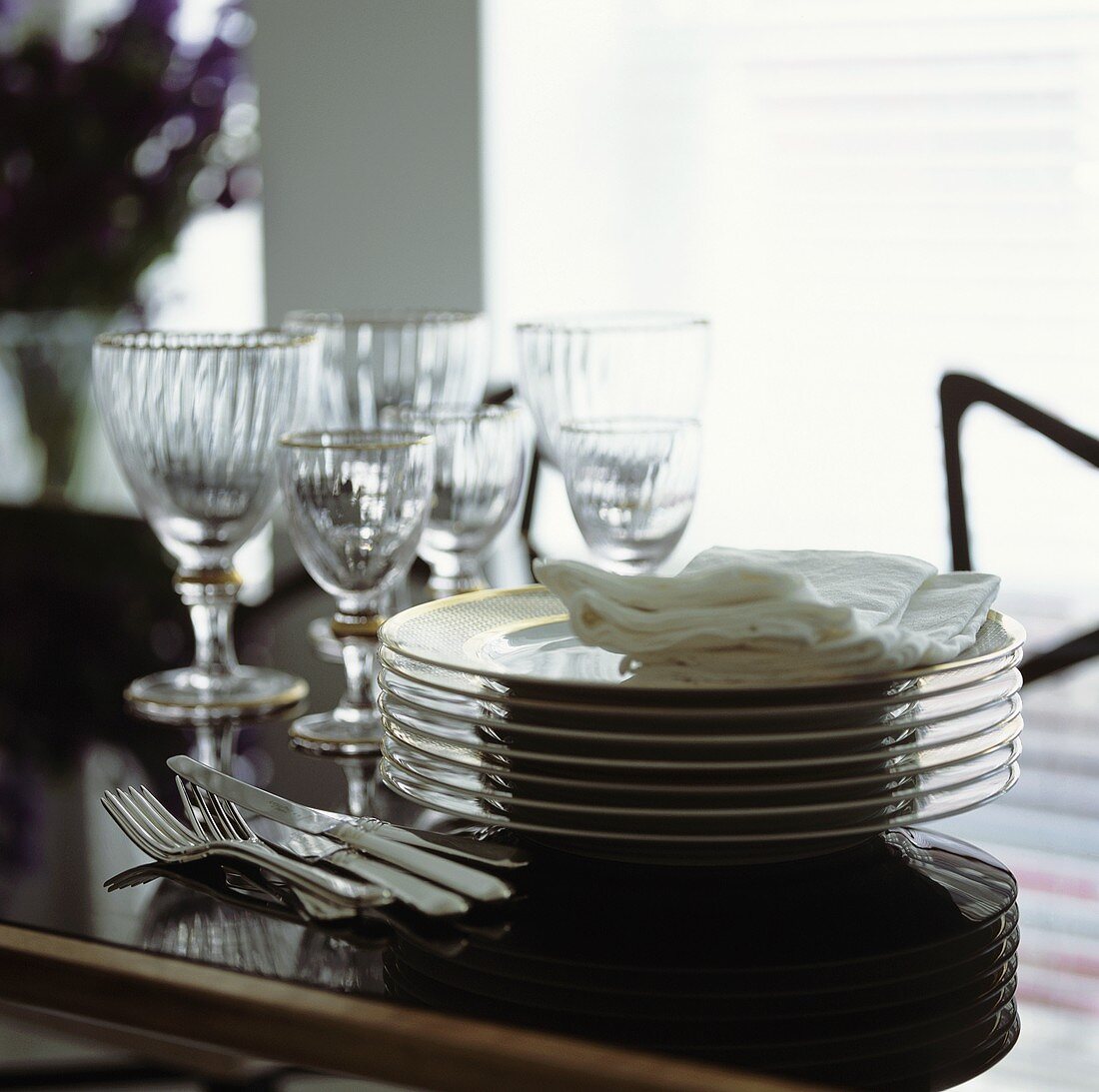 Pile of plates, cutlery and glasses on a dining table