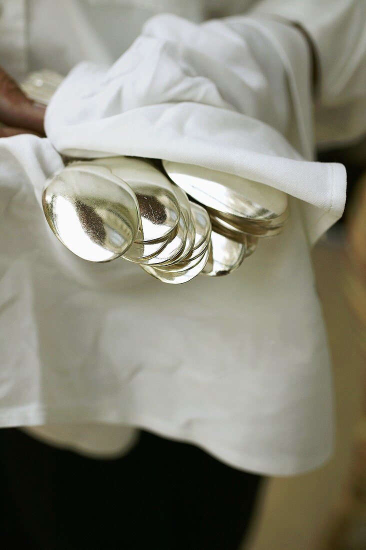 Waiter holding spoons in a cloth