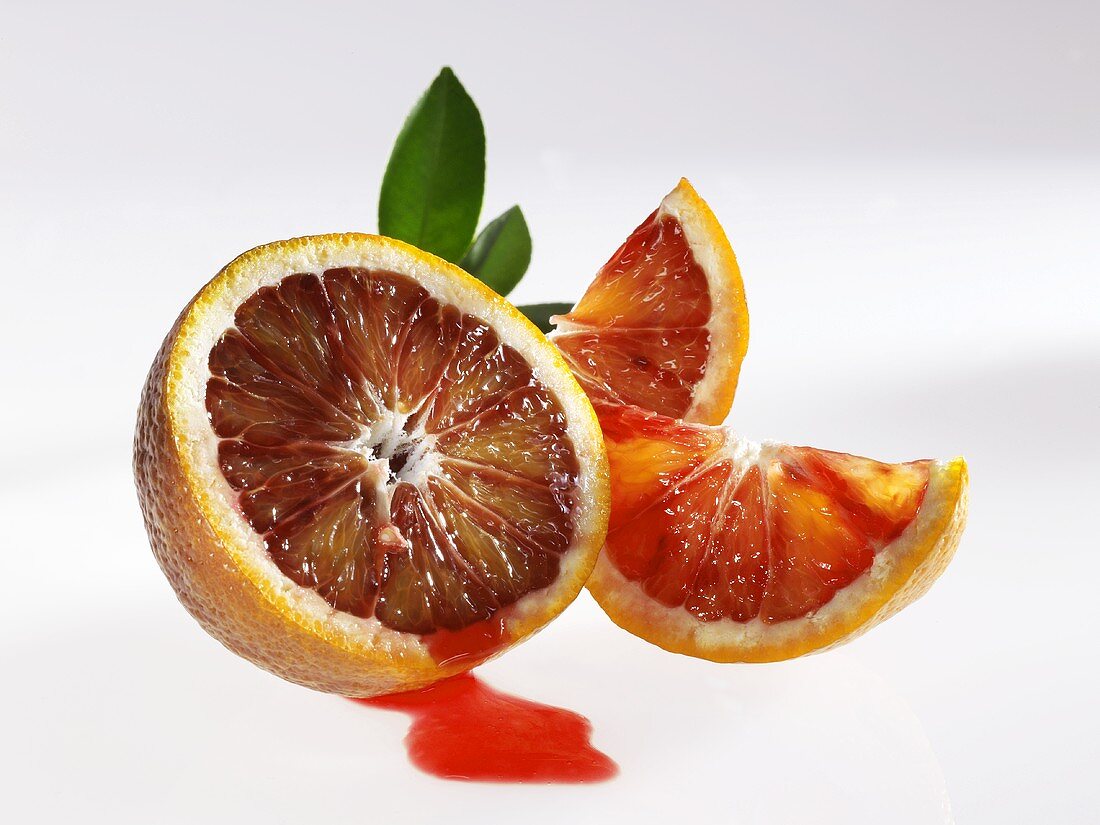 Half a blood orange with juice and wedges of blood orange