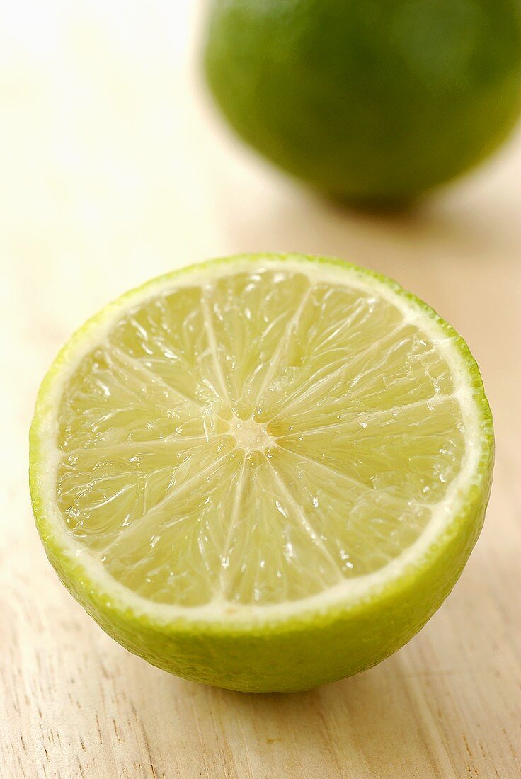 Eine halbe Limette mit ganzer Limette im Hintergrund