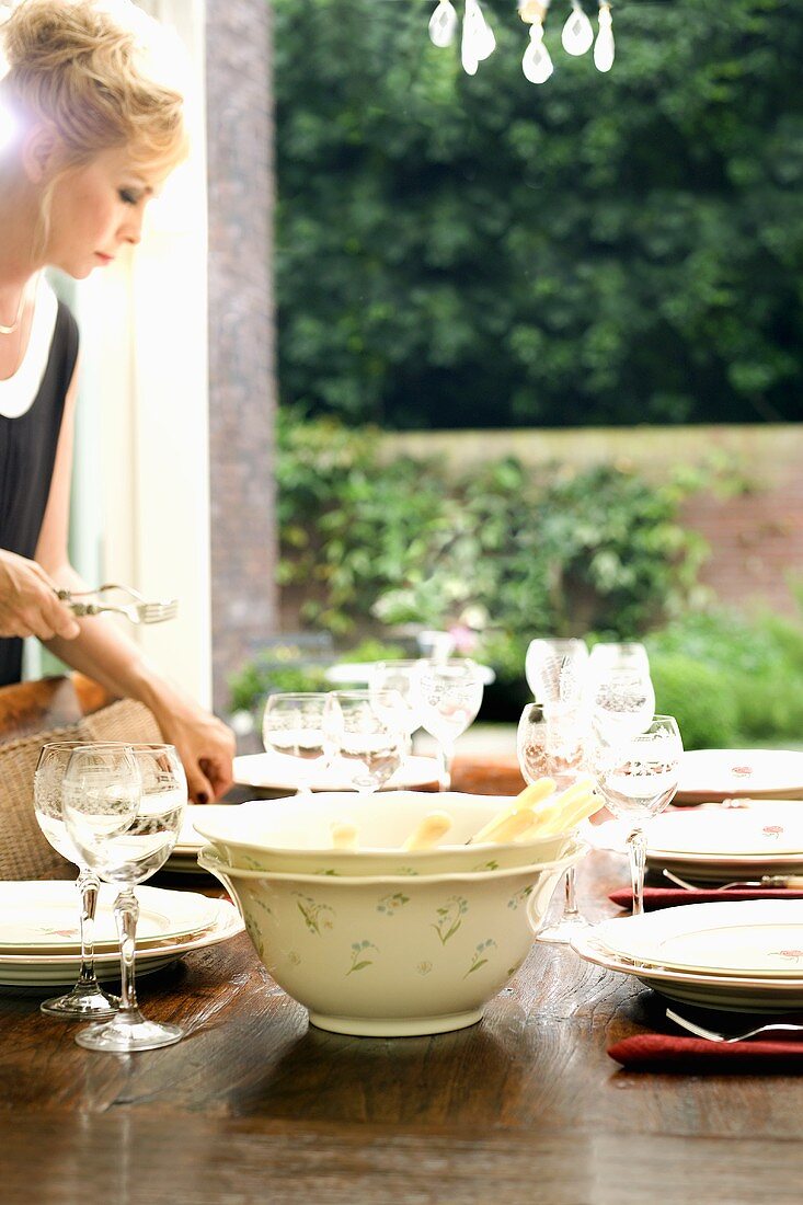 Woman laying table on terrace