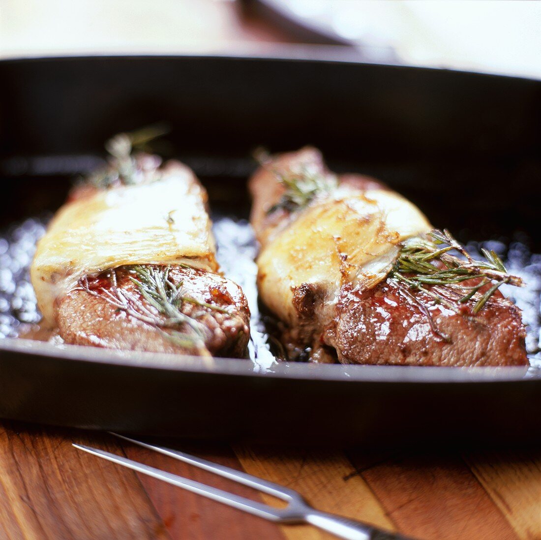Steaks topped with rosemary and melted cheese