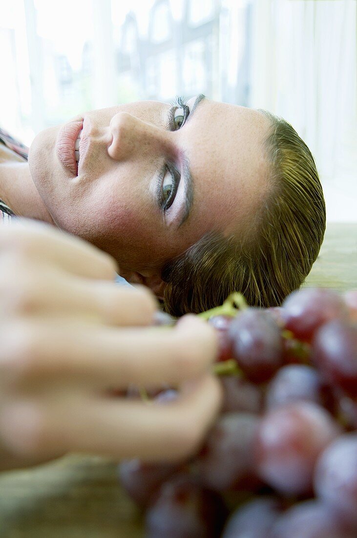 Woman, lying down, reaching for grapes