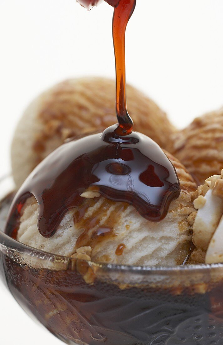 Pouring caramel sauce over an ice cream sundae