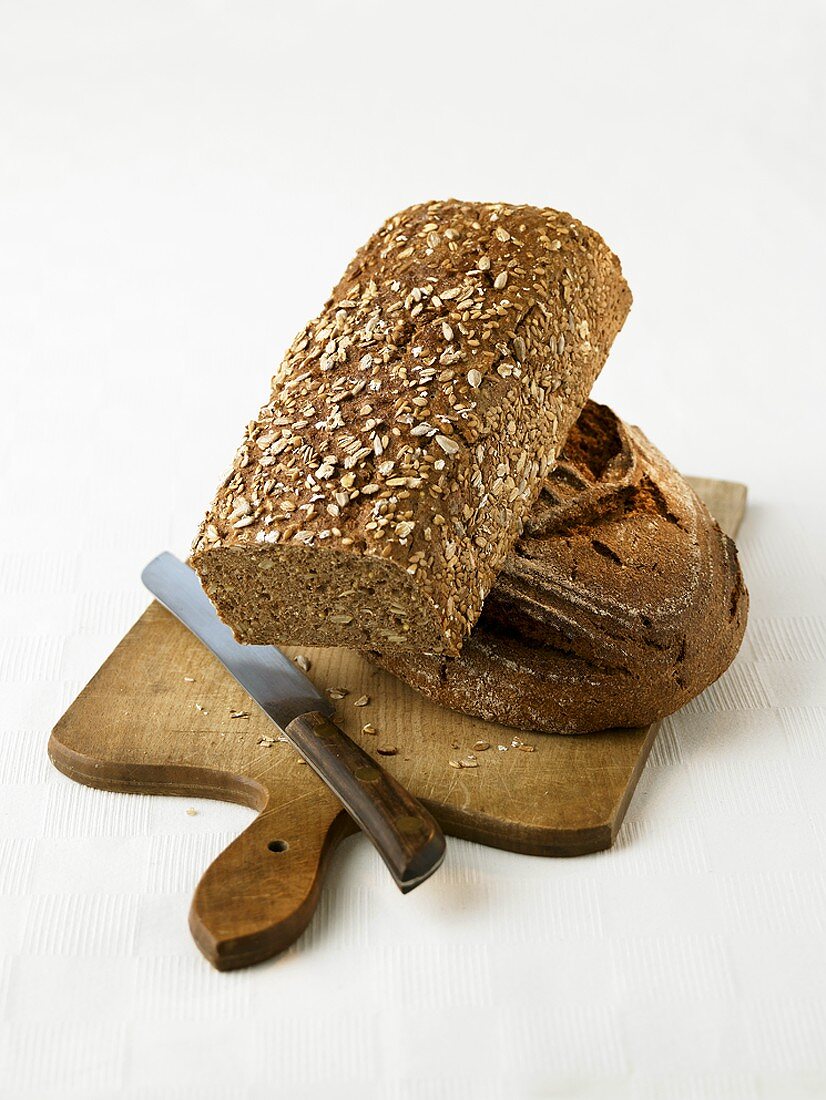 Zwei Laib Brot auf einem Brett mit Messer