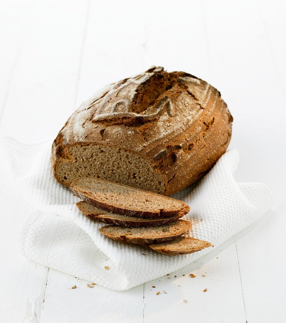 A loaf of rye bread, partly sliced