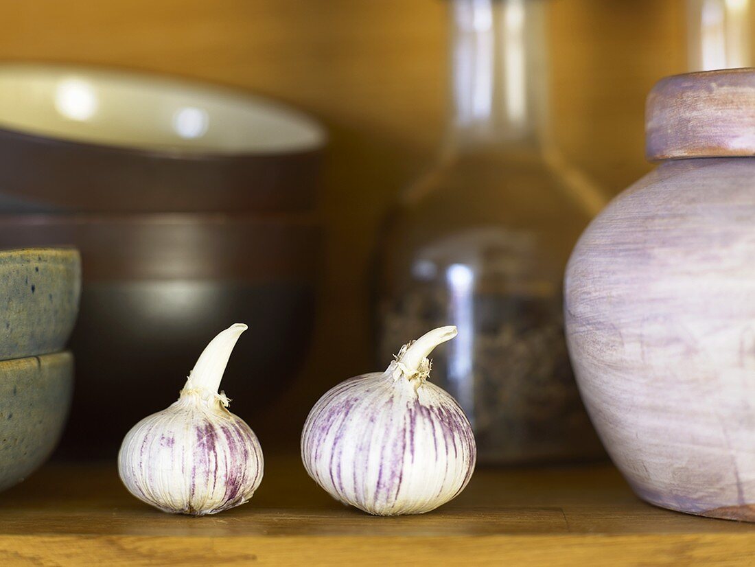 Two garlic bulbs on a kitchen shelf