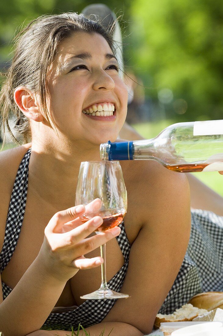 Smiling woman having a glass of rosé wine poured