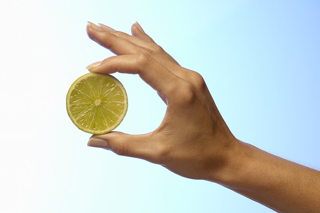 Woman's hand holding half a lime