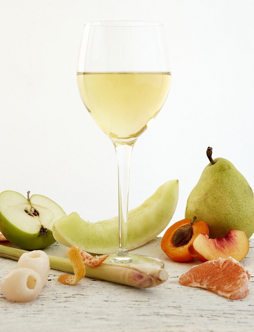 A glass of white wine surrounded by fruit