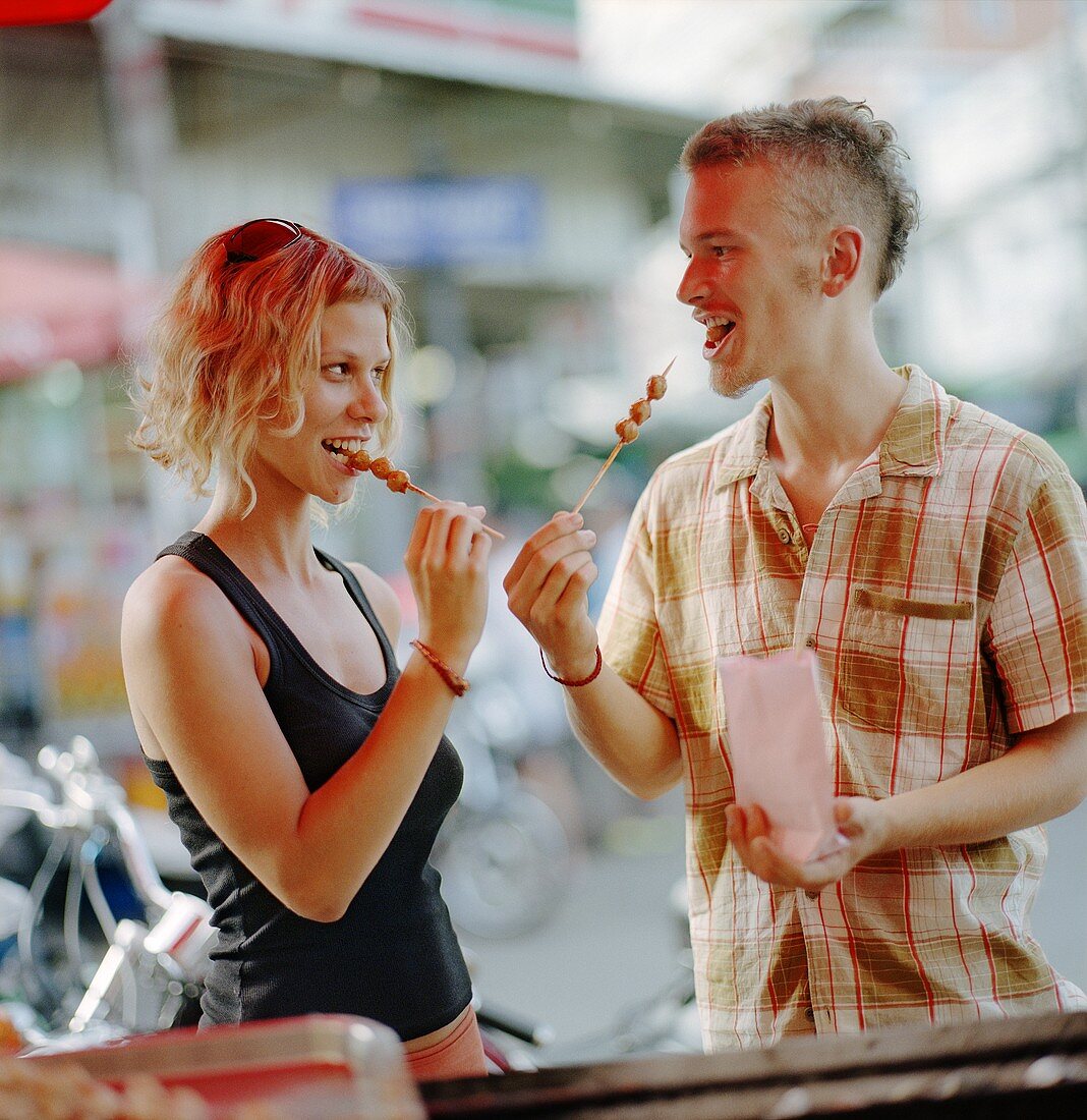 Young couple eating chocolate fruit skewers
