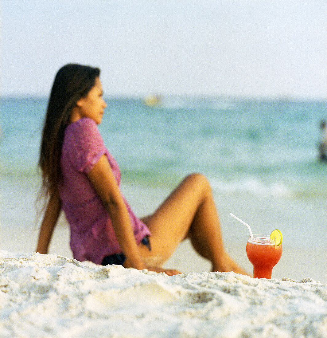 Frau mit Singapore Sling am Strand