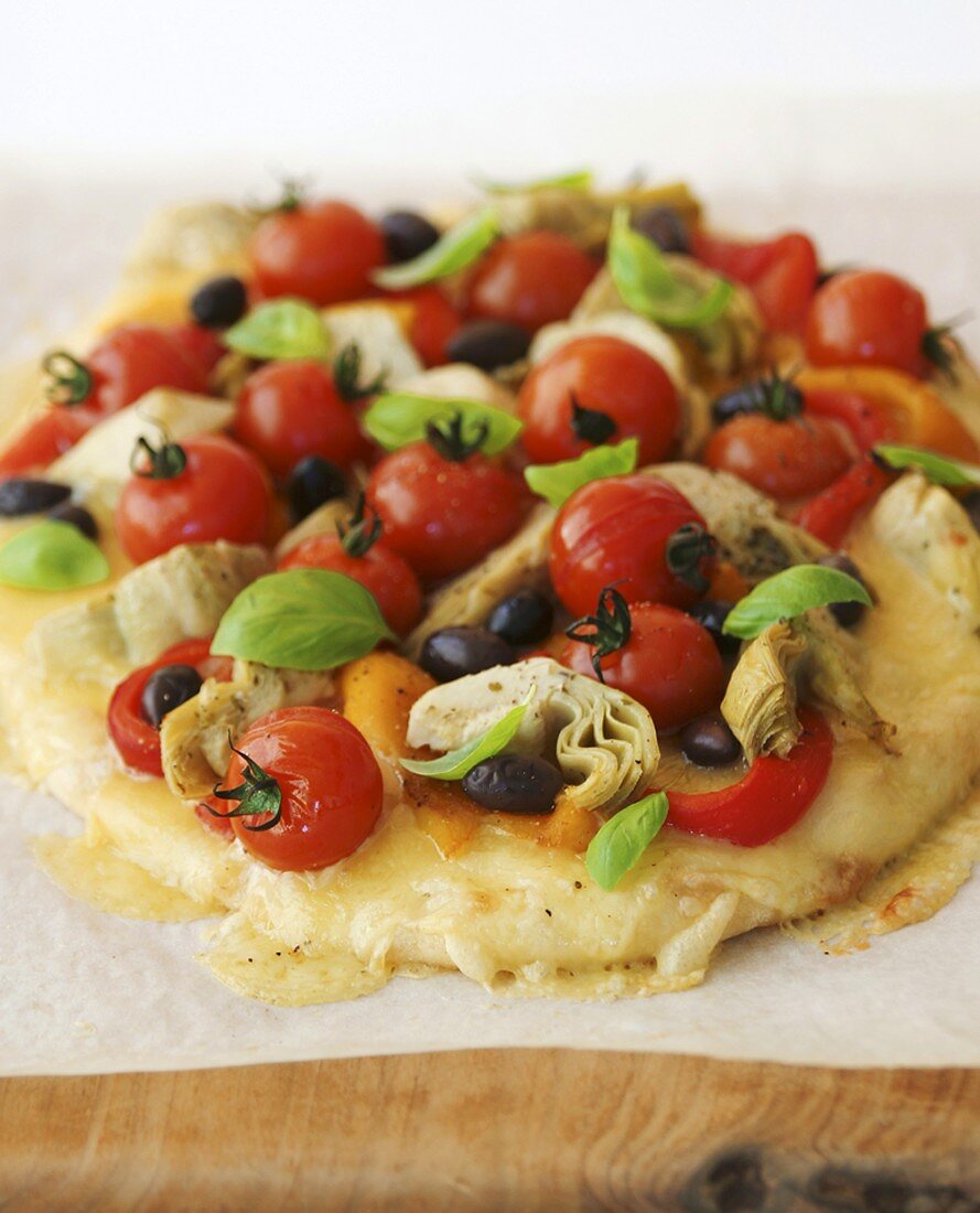 Pizza topped with tomatoes, olives and artichokes