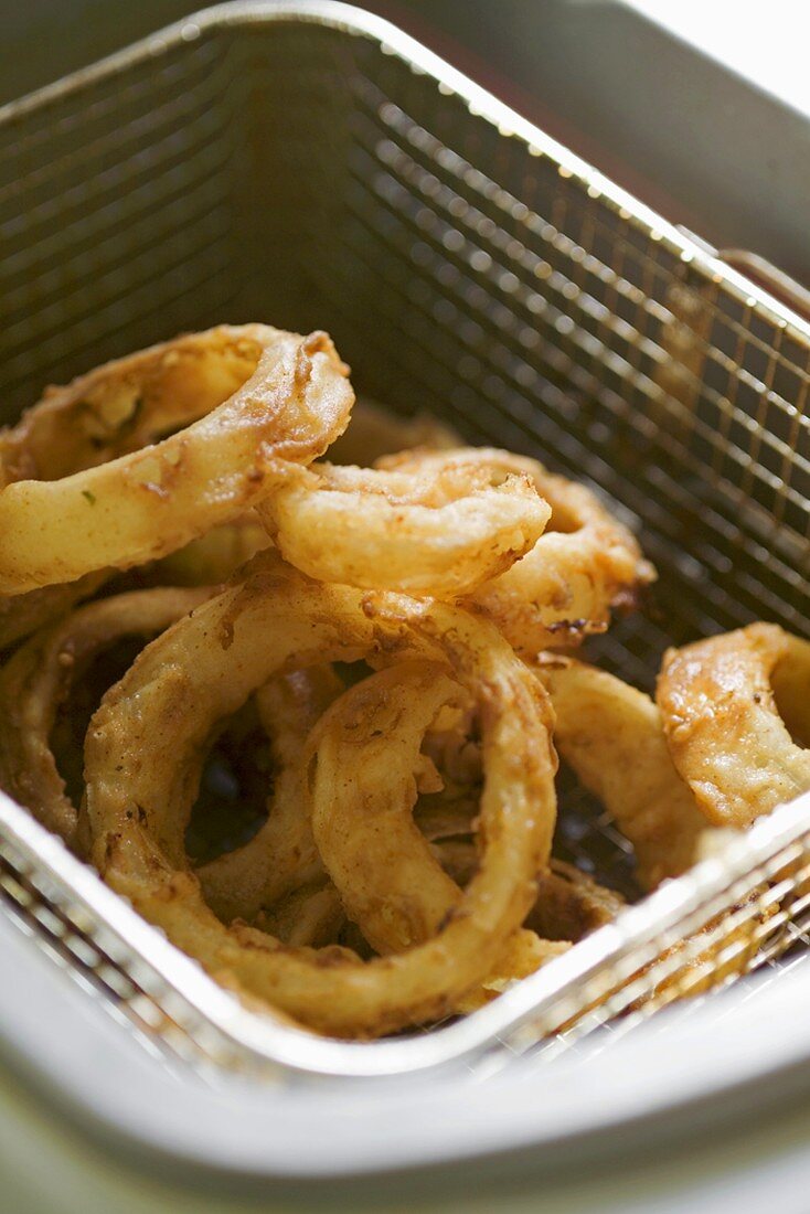 Deep-fried onion rings in basket of deep fat fryer