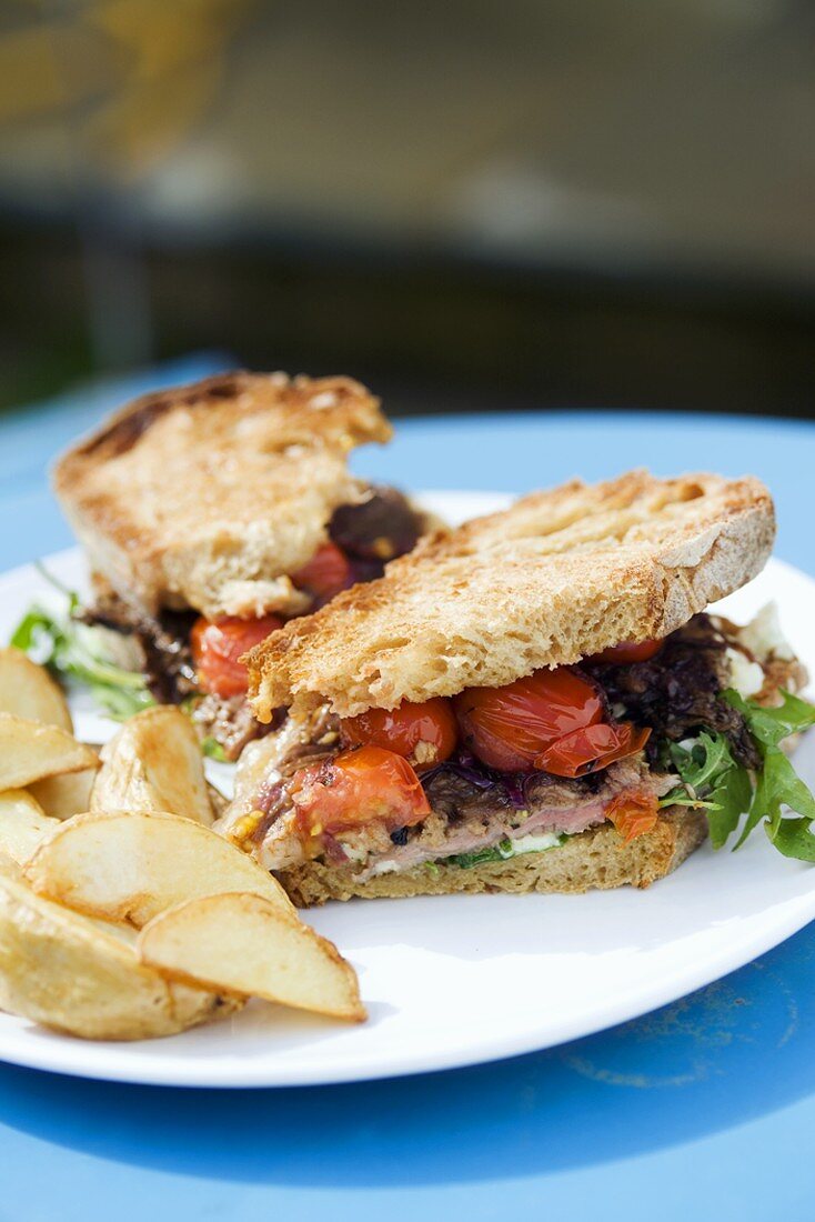 Steak and tomato sandwich with potato wedges