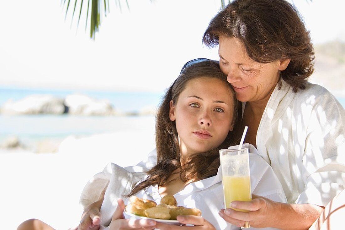 Mutter und Tochter mit einem Snack am Strand