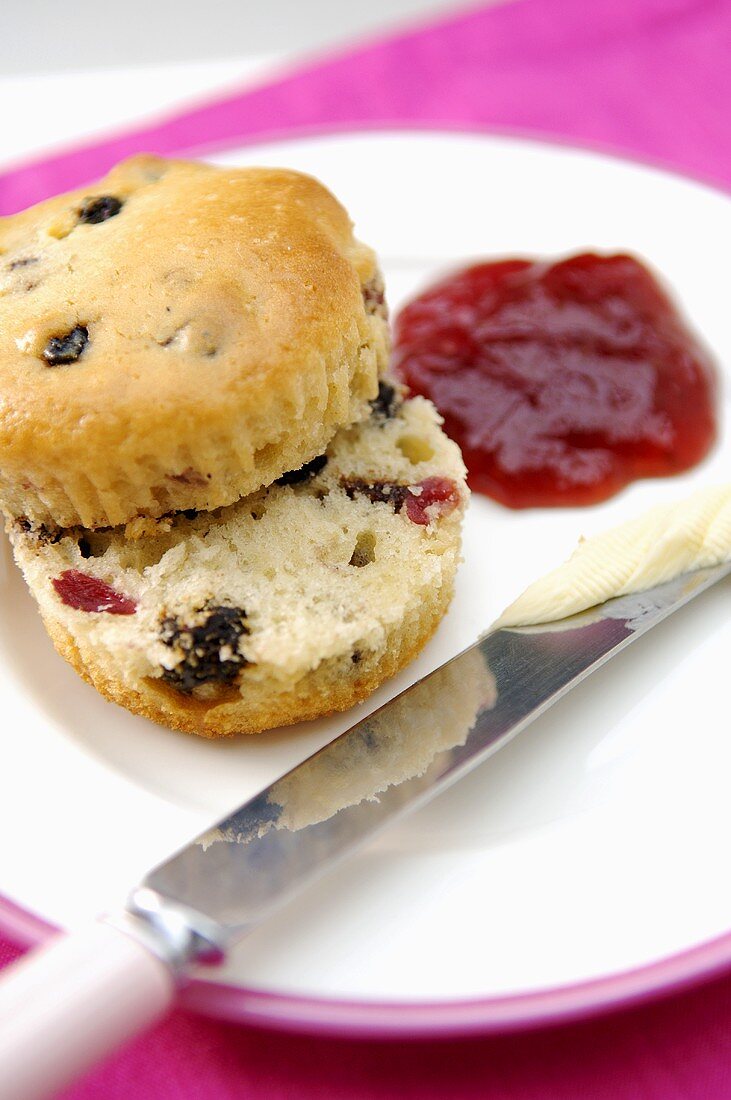 Halbierter Muffin mit Trockenfrüchten, Butter und Konfitüre