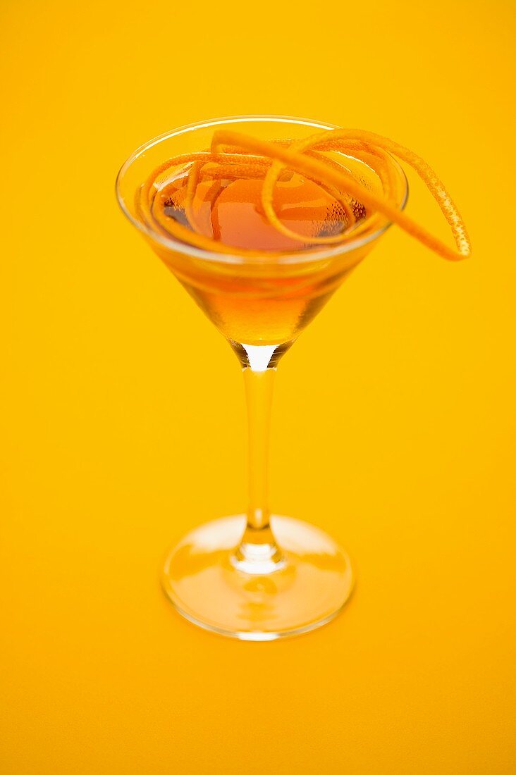 An orange cocktail with orange zest