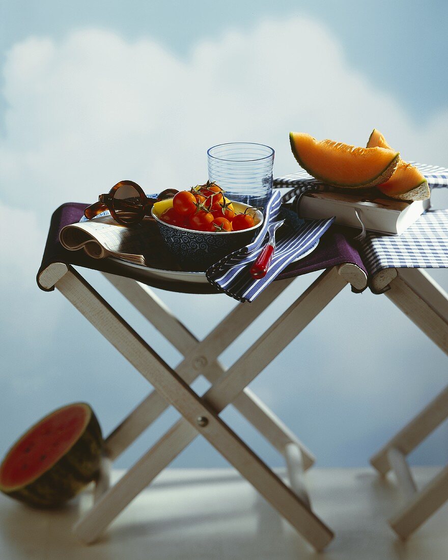 Sommerküche: Melone, Tomaten auf Hockern, Buch, Sonnenbrille