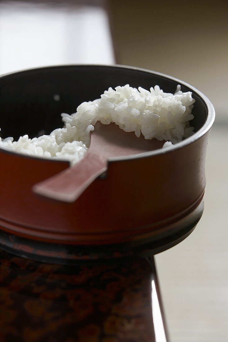 Cooked rice in a wooden bowl with wooden spoon