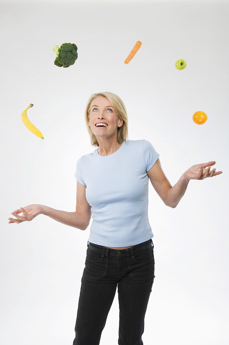 A woman juggling fruit and vegetables