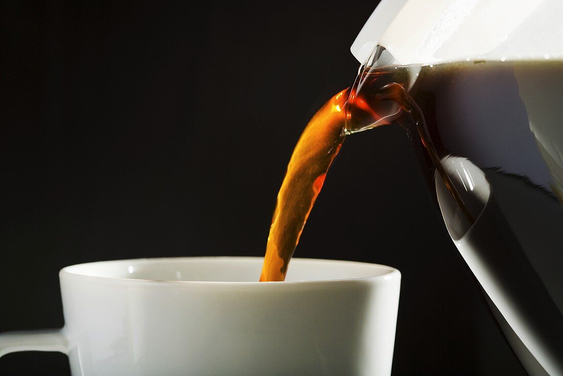 Coffee being poured into a cup from a jug