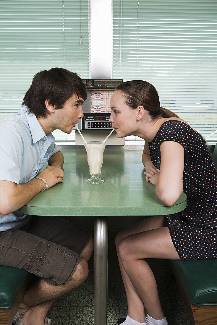 A young couple drinking a milkshake