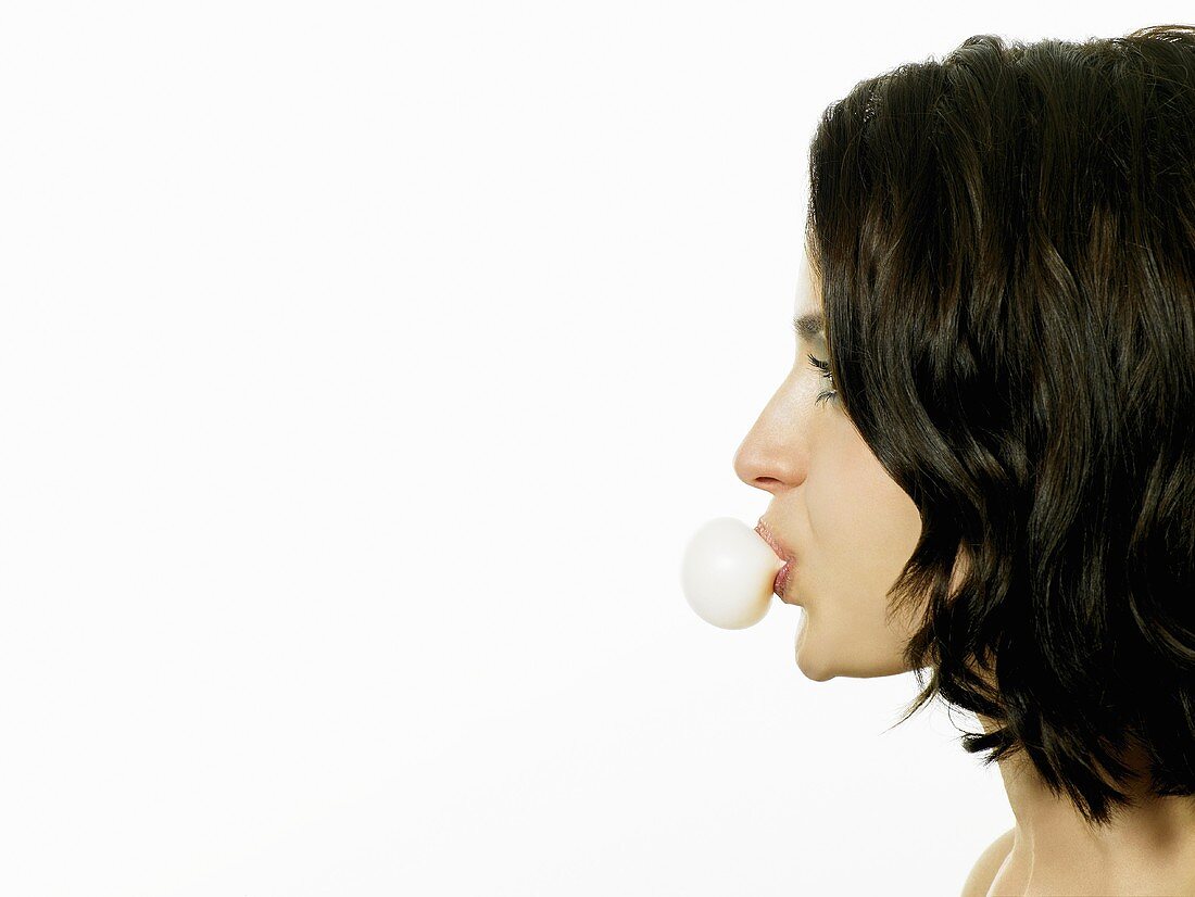 A young woman blowing a bubble with chewing gum
