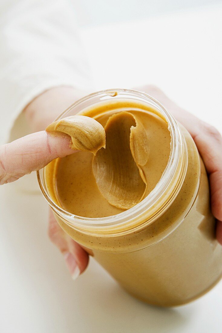 A woman scooping peanut butter out of a jar