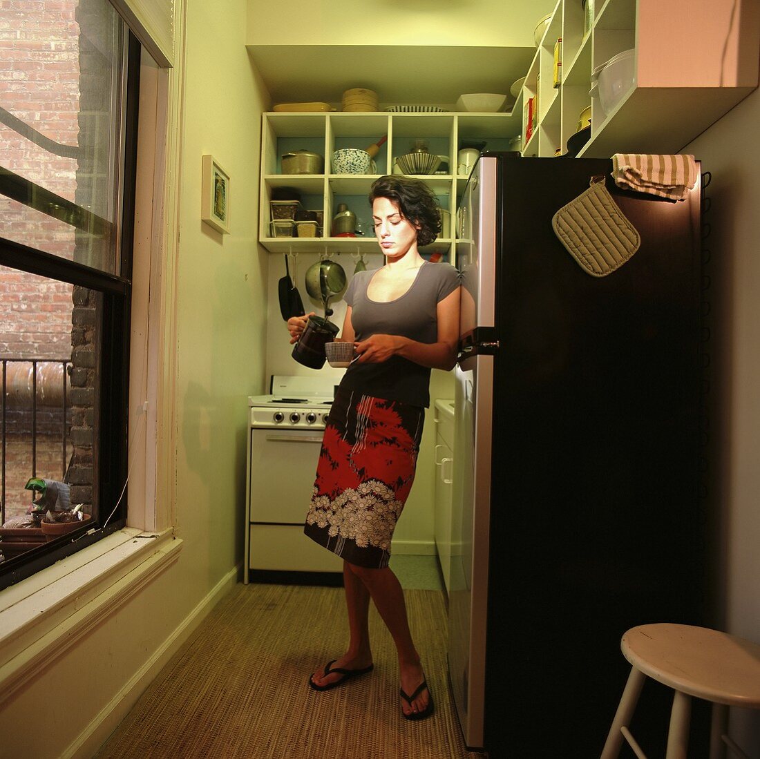 Frau giesst sich Kaffee in der Küche ein