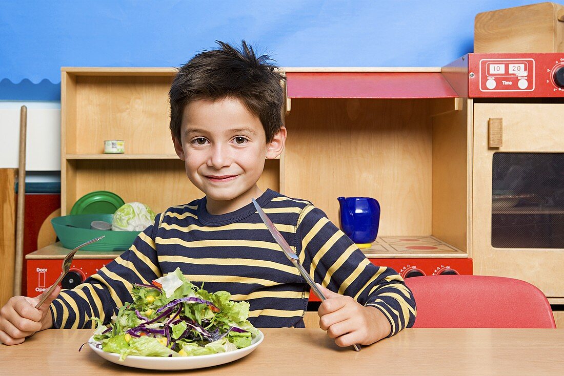 A boy with a plate of salad