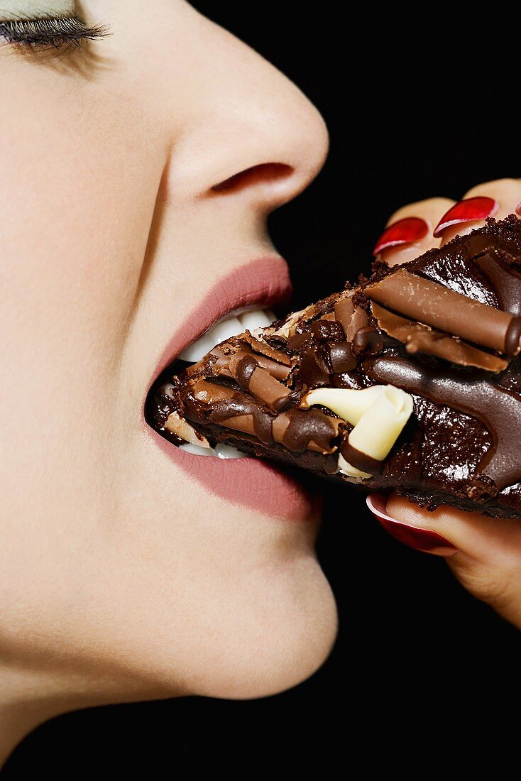 A woman eating a chocolate cake