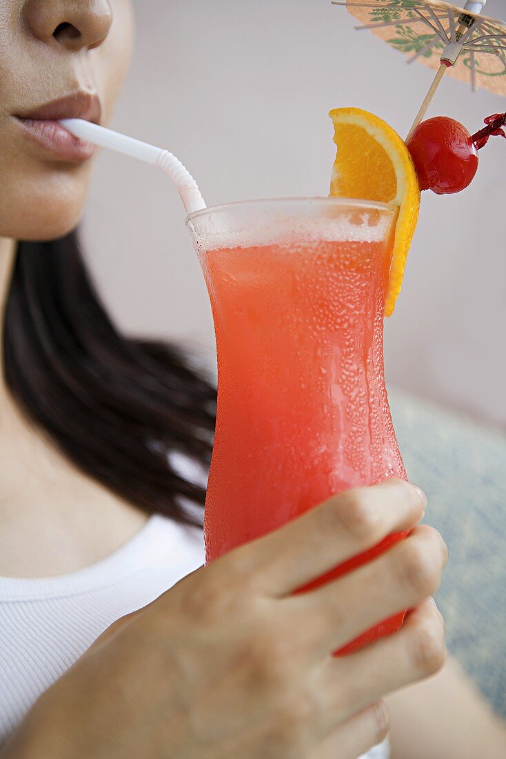 A woman drinking a cocktail through a straw