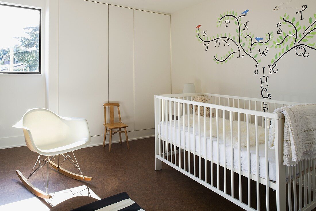 Babyzimmer mit weißem Gitterbett, Wandmalerei & Schaukelstuhl