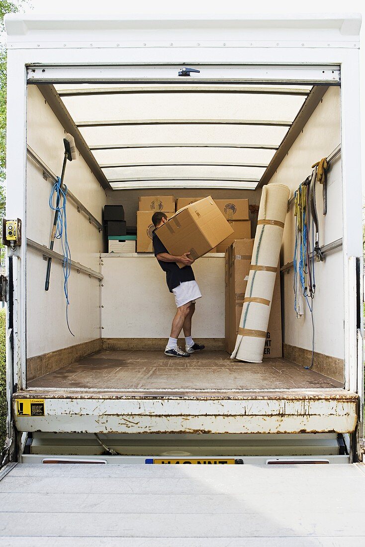 Mann mit Umzugskartons in einem Möbelwagen
