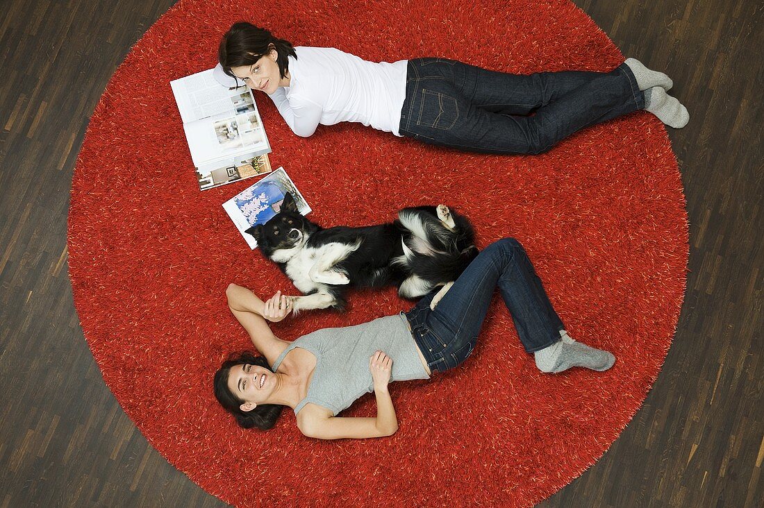 A women and a dog lying on a rug