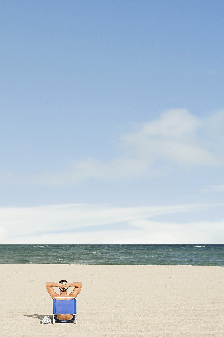 A man sitting on a chair at the beach