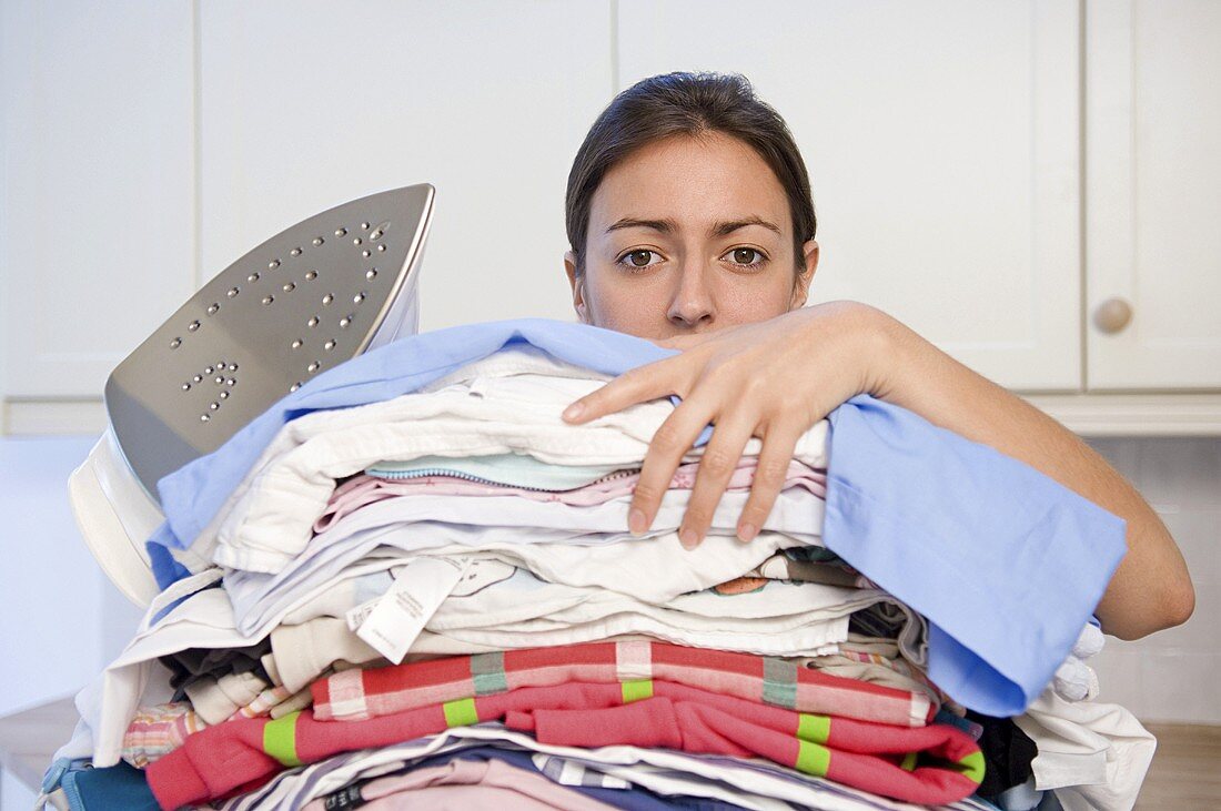 A woman holding stack of ironing